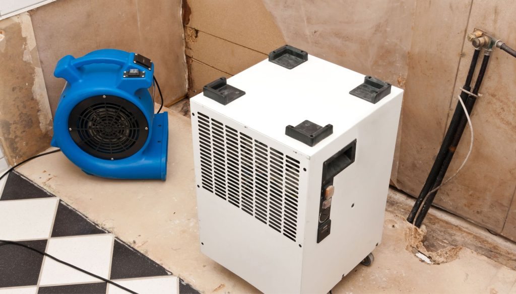 A dehumidifier and fan are set-up in a room to remove moisture during water damage cleanup in a home in Carmel, IN.